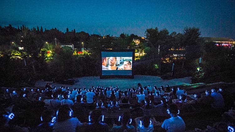 Cinéma en plein air, public au casque devant un écran