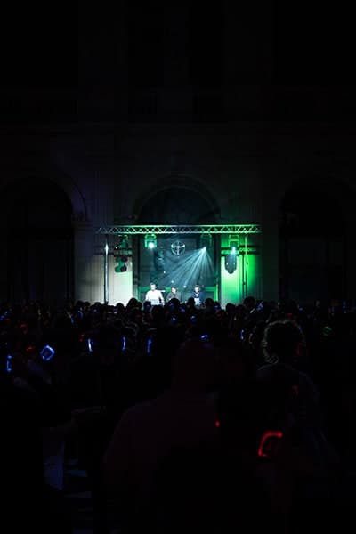 Foule de dos, casques allumés en bleu et vert face à la scène